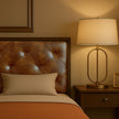 Elegant king bed with tufted leather headboard, warm bedside lamp, and cozy pillows in a stylish bedroom setting.